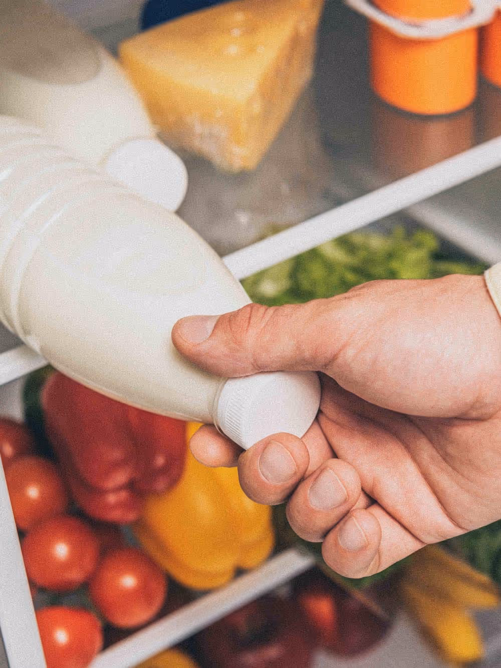 A hand taking a bottle of milk from a fridge