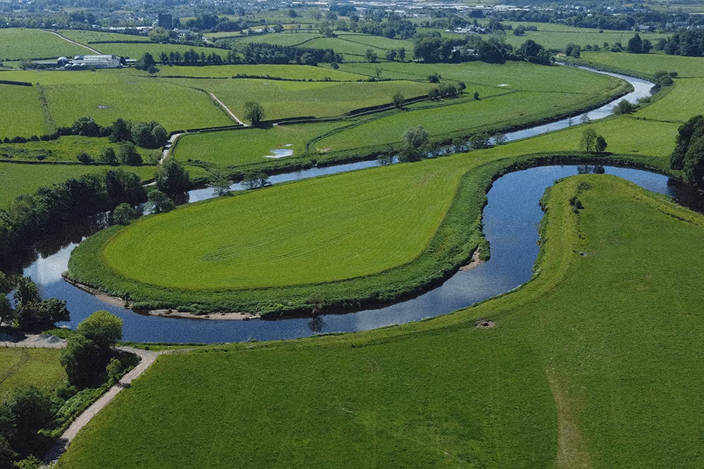 Aerial view of a river winding through green farmland