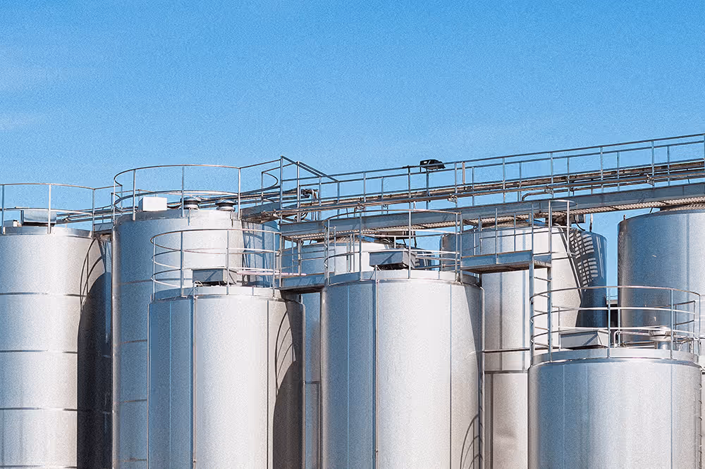 Steel silos at a processing plant under a blue sky